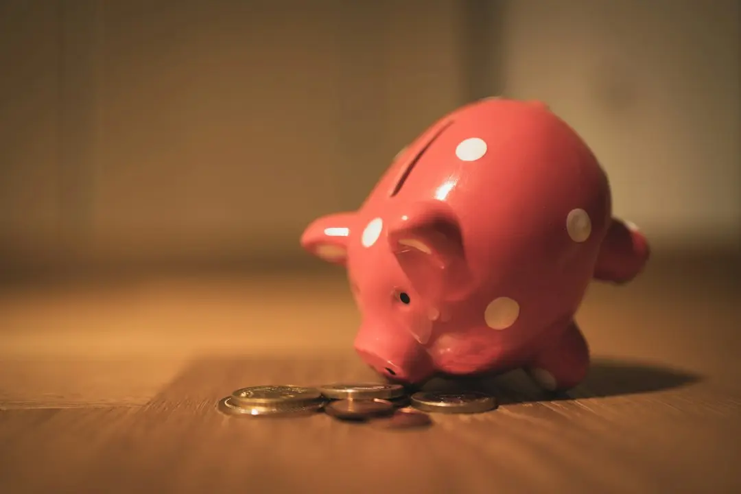 A red polka-dot piggy bank beside a few coins on a wooden table, a reminder to check what cheap IPTV really costs