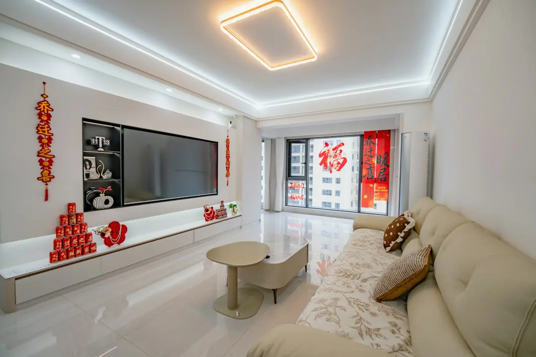 A large flat-screen TV set into a white wall unit in a bright, modern living room, the kind of screen premium IPTV plays on
